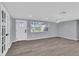 Large living room featuring gray walls, wood-look floors, ceiling fan, and a decorative front door at 6706 Sierra Ter, New Port Richey, FL 34652