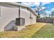 A view of the side yard showing the home's exterior and HVAC system, and a partial fence at 6706 Sierra Ter, New Port Richey, FL 34652
