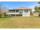 Exterior of home featuring a screened porch, sliding glass doors, and a spacious yard at 1007 Lake Avoca Dr, Tarpon Springs, FL 34689