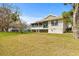 Home's back exterior with a porch, sliding doors, and a well-maintained lawn at 1007 Lake Avoca Dr, Tarpon Springs, FL 34689