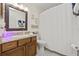 Well-lit bathroom featuring a wooden vanity, granite countertop, and a shower with a white curtain at 1007 Lake Avoca Dr, Tarpon Springs, FL 34689