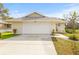 Home featuring a well-maintained lawn, driveway, and a two-car garage in a sunny neighborhood at 1007 Lake Avoca Dr, Tarpon Springs, FL 34689
