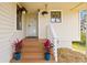 Charming front porch with colorful potted plants, wooden stairs, and white railings at 1007 Lake Avoca Dr, Tarpon Springs, FL 34689