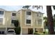 Exterior view of townhome with garages, mature trees, and driveway parking at 102 Brent Cir, Oldsmar, FL 34677