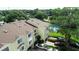 Aerial view of a yellow townhome community with well-maintained landscaping, a tennis court, and ample parking at 102 Brent Cir, Oldsmar, FL 34677