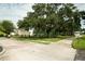 A street view with a tennis court in the distance, manicured bushes, and lush trees at 102 Brent Cir, Oldsmar, FL 34677