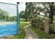 A neighborhood tennis court has green fencing and borders a sidewalk and some grass at 102 Brent Cir, Oldsmar, FL 34677