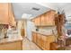 Well-lit kitchen featuring wooden cabinets, updated countertops, tiled backsplash, and modern appliances at 15808 Sea Pines Dr, Hudson, FL 34667