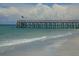 Picturesque pier extending into the ocean with clear water, sandy beach, and beautiful cloudscape in the background at 16333 Gulf Blvd # 106, St Petersburg, FL 33708