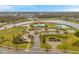 Aerial view of a community center featuring a clubhouse, pool, playground, walking paths, and tennis courts near a pond at 5045 Ivory Stone Dr, Wimauma, FL 33598