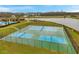 A high angle view of three tennis courts inside of a black chain link fence surrounded by lush green grass at 5045 Ivory Stone Dr, Wimauma, FL 33598