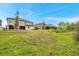 Large backyard with lush grass, surrounded by trees and other houses at 5045 Ivory Stone Dr, Wimauma, FL 33598