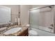 Bathroom showcasing a granite countertop, sink, toilet, and bathtub with sliding glass doors and showerhead at 5045 Ivory Stone Dr, Wimauma, FL 33598