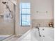 Bright bathroom featuring tile flooring, a bathtub, and a glass enclosed shower with a showerhead at 5045 Ivory Stone Dr, Wimauma, FL 33598