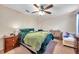 A comfortable bedroom with ceiling fan, plush green bedding, wood dresser, and chaise lounge at 5045 Ivory Stone Dr, Wimauma, FL 33598