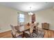 Dining room with wood floors features a chandelier, large windows with curtains and view of the kitchen at 5045 Ivory Stone Dr, Wimauma, FL 33598