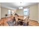 Dining room with wood floors features a chandelier and large windows with curtains and nearby plants at 5045 Ivory Stone Dr, Wimauma, FL 33598