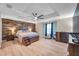 Main bedroom with a wooden accent wall, light wood floors, fan, tray ceiling, and a large window at 5045 Ivory Stone Dr, Wimauma, FL 33598