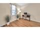 Office with wood floors features a desk, a chair, a lamp, plants, and a large window with curtains at 5045 Ivory Stone Dr, Wimauma, FL 33598