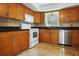 Kitchen with wood cabinets, stainless dishwasher, white appliances, and granite countertops at 3087 Duane Ave, Oldsmar, FL 34677