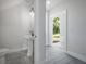 Bright bathroom with pedestal sink, gray flooring and open doorway to the outside at 3801 Luma Dr, Holiday, FL 34691
