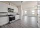 Open-concept kitchen with white cabinets, stainless steel appliances, and wood-look flooring at 3801 Luma Dr, Holiday, FL 34691