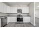 Modern kitchen with stainless steel appliances, white cabinetry, granite countertops, and gray laminate flooring at 3801 Luma Dr, Holiday, FL 34691