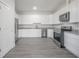 Modern kitchen featuring white cabinetry, stainless steel appliances, granite countertops, and gray laminate flooring at 3801 Luma Dr, Holiday, FL 34691