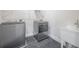 Laundry area equipped with washer, dryer, utility sink, and modern gray tile flooring at 3801 Luma Dr, Holiday, FL 34691
