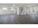 Spacious living room with gray wood-look flooring, white walls, and stairway at 3801 Luma Dr, Holiday, FL 34691