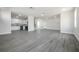 Open concept living area with light gray wood-look floors, white walls, and a kitchen visible in the background at 3801 Luma Dr, Holiday, FL 34691