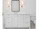 Elegant bathroom vanity with white cabinets, countertop, and a sleek black framed mirror with stylish sconces at 4614 W Tennyson Ave, Tampa, FL 33629