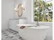 Bright bathroom with a freestanding tub, wooden bath tray, and a view of lush landscaping through a large window at 4614 W Tennyson Ave, Tampa, FL 33629