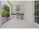 Outdoor kitchen with stainless steel grill, fridge, sink, white stone floor and black railing at 4614 W Tennyson Ave, Tampa, FL 33629