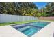 Backyard swimming pool with light stone tiling and surrounded by trees and a privacy fence at 4614 W Tennyson Ave, Tampa, FL 33629