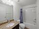 Bright bathroom featuring granite countertops, a modern sink, and a shower with a blue-striped curtain at 4734 Chatterton Way, Riverview, FL 33578