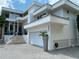 Stunning modern home featuring clean lines, a two-car garage, and lush tropical landscaping at 1522 Gulf Blvd, Indian Rocks Beach, FL 33785