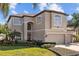 Two-story home featuring neutral stucco, manicured landscaping, and a three-car garage, showcasing curb appeal at 1881 Riveredge Dr, Tarpon Springs, FL 34689