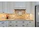 Close-up of the kitchen's cooktop and hood with custom cabinetry, granite countertops, and stylish backsplash at 1881 Riveredge Dr, Tarpon Springs, FL 34689