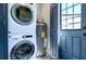 Modern laundry room featuring stacked washer and dryer and space-saving water heater near the entryway at 245 58Th N St, St Petersburg, FL 33710