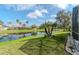 Scenic backyard view featuring a serene pond, palm trees, and well-maintained green lawn at 27045 Firebush Dr, Wesley Chapel, FL 33544