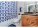 Cozy bathroom with a blue patterned shower curtain, vanity with granite countertop, and wood-finished cabinets at 27045 Firebush Dr, Wesley Chapel, FL 33544