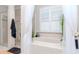 Bright bathroom features a soaking tub, a separate shower with glass door, and a window with plantation shutters at 27045 Firebush Dr, Wesley Chapel, FL 33544