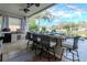 Outdoor kitchen features a built-in grill, bar seating, and view of pool and patio at 27045 Firebush Dr, Wesley Chapel, FL 33544