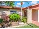 Close-up of front entrance landscaping featuring a small palm tree, pink flowers, and other plant life at 7425 118Th Dr, Largo, FL 33773