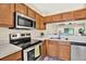 Well lit kitchen featuring stainless steel appliances, wood cabinets, and view to dining area at 8541 Hunters Key Cir, Tampa, FL 33647
