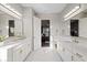 Bright bathroom with double vanity sinks, white cabinets, marble countertops, and white marble flooring at 4188 Barbour Trl, Odessa, FL 33556