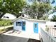 Charming white cottage with blue doors and shutters surrounded by lush trees at 14124 Plum Ln, Hudson, FL 34667