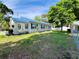 Expansive yard with lush green grass and mature trees, with a charming home in the background at 14124 Plum Ln, Hudson, FL 34667