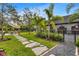 Backyard featuring stone walkway leading to patio with dining set, lush landscaping, and garage in the background at 3005 S Miller Rd, Valrico, FL 33596